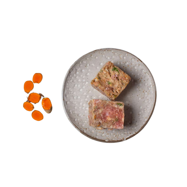 Zwei quadratische Stücke gemischtes Hackfleisch auf einem grauen, rundem Teller neben mehreren geschnittenen Karottenscheiben.