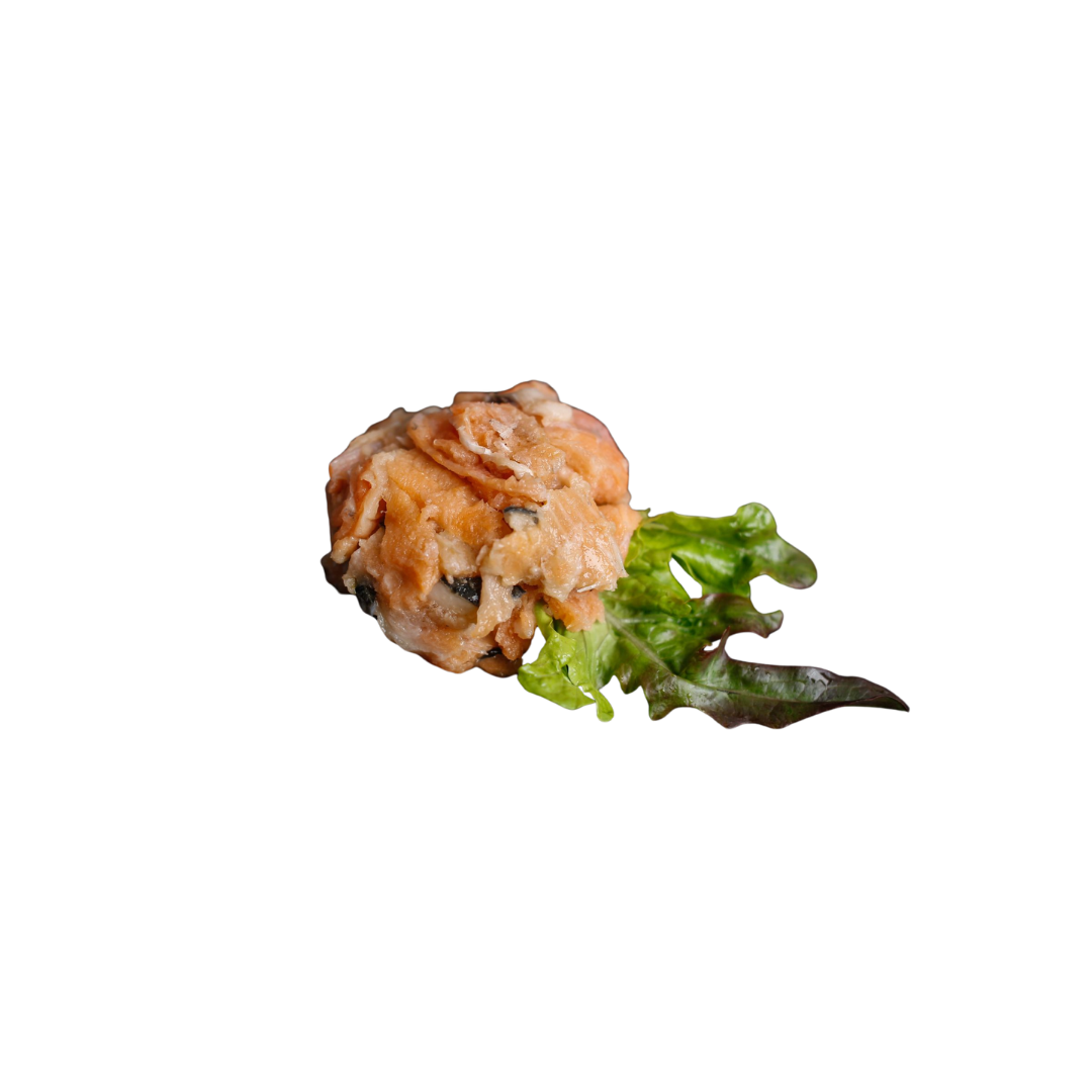 Stück roher Lachs auf weißem Untergrund mit grünem Salatblatt