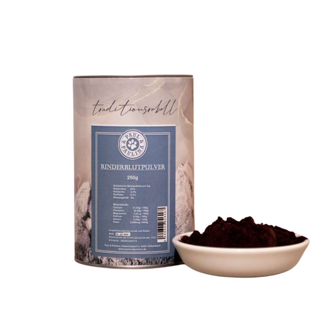 Zylindrische Verpackung mit blauem Etikett 'Rinderblutpulver 250g' neben weißer Schale mit dunkelrotem Pulver.