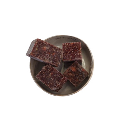 Vier fast quadratische Stücke gemischtes Fleischwürfel auf einem grauen, rundem Teller.