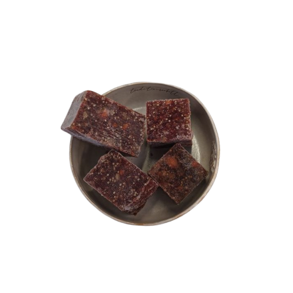 Vier fast quadratische Stücke gemischtes Fleischwürfel auf einem grauen, rundem Teller.