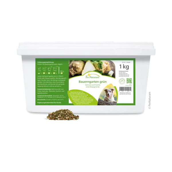 Weißer Behälter mit grünem Etikett der Marke PerNaturam, 1kg, Produktname 'Bauerngarten grün', mit Text "Gemüse und Früchte ohne Rotpigmente" und einem Bild eines braun und weißen Hundes, davor lose Kräutermischung.