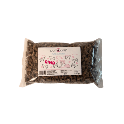 PuriCanis Pure Häppchen Rind, 500g Packung mit braunen, rechteckigen Hundeleckerlis, auf der Verpackung Zeichnungen von Rindern und einem Hund.