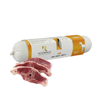 Verpackte Fleischrolle mit Lamm von Ritzenberger, daneben rohe Lammfleischstücke