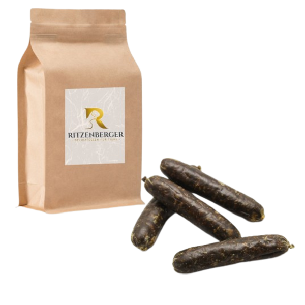Braune Papiertüte mit Aufkleber 'Ritzenberger' neben vier dunkelbraunen, länglichen Würsten.
