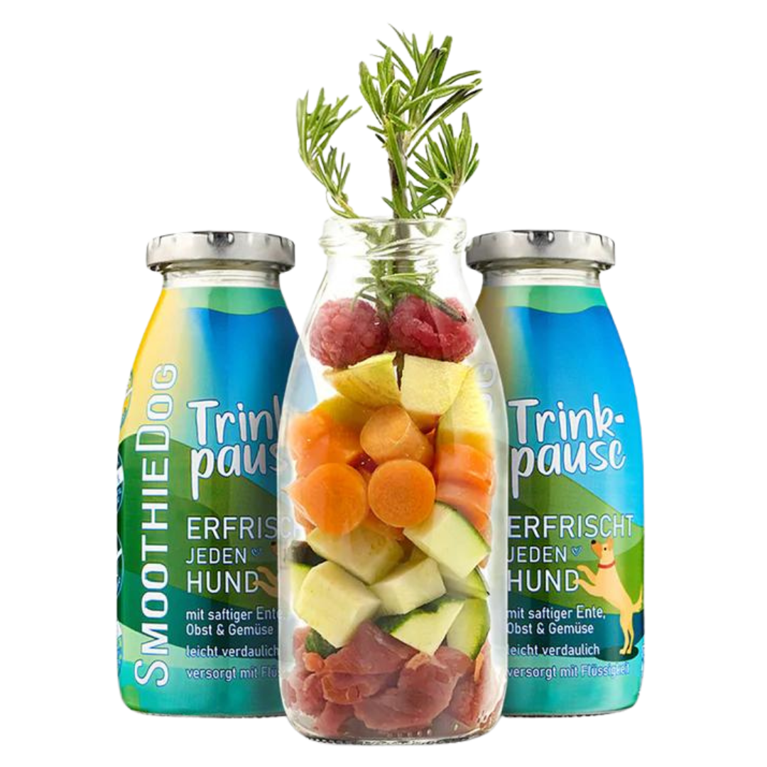 Zwei Flaschen SmoothieDog Trinkpause mit Ente, Obst und Gemüse, davor Glasflasche mit geschnittenem Obst, Gemüse, Himbeeren und Rosmarinzweig.