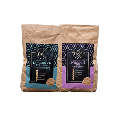 Zwei braune Papiertüten mit blau und violett Etiketten, beschriftet mit 'mysignature Ente und Hirsch Duck and Deer', Weiderind,Beef jeweils mit goldfarbenem Siegelaufkleber