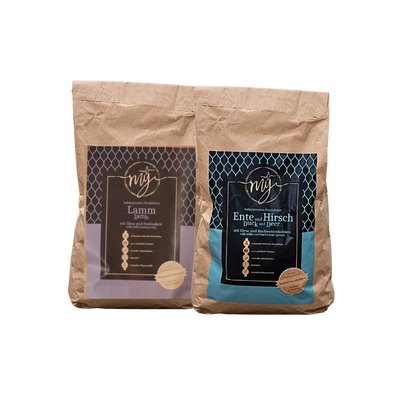Zwei braune Papiertüten mit blau und violett Etiketten, beschriftet mit 'mysignature Ente und Hirsch Duck and Deer und Lamm, Lamp jeweils mit goldfarbenem Siegelaufkleber.