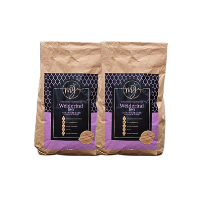 Zwei braune Papiertüten mit violetten Etiketten, beschriftet mit 'mysignature Weiderind, Beef jeweils mit goldfarbenem Siegelaufkleber.