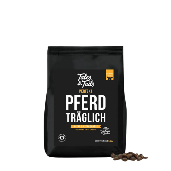Schwarze Verpackung von Tales & Tails halbfeuchtem Trockenfutter mit der Aufschrift 'Perfekt Pferd träglich', daneben einige braune Futterstücke.