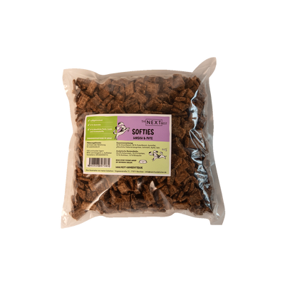 Transparente Verpackung mit 500 g Softies von der Marke 'NEXT'. Die Softies haben eine unregelmäßige Form und sind braun. Auf der Vorderseite befindet sich ein Etikett mit Produktinformationen.