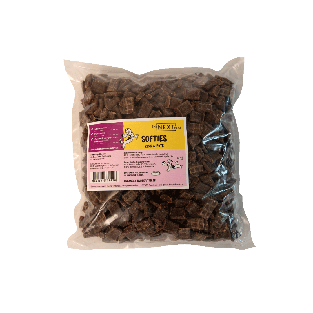 Transparente Verpackung mit 500 g Softies von der Marke 'NEXT'. Die Softies haben eine unregelmäßige Form und sind braun. Auf der Vorderseite befindet sich ein Etikett mit Produktinformationen.