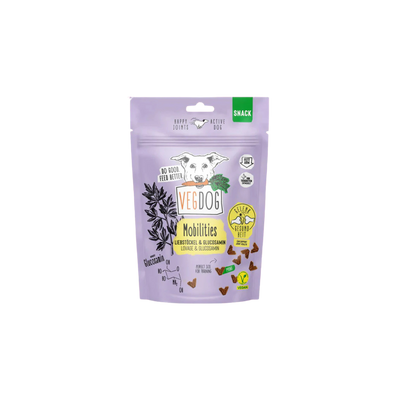 Lila Verpackung mit Hundekopf, Text 'VEGDOG Mobilities', kleine braune dreieckige Hundesnacks, Symbole für vegan und glutenfrei.