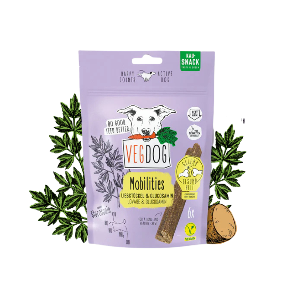 Lila Verpackung von Vegdog Mobilities Kausnack mit Hundekopf-Illustration, Text 'Liebestöckel & Glucosamin', sechs vegane Snacks, umgeben von Pflanzen und Kartoffeln.